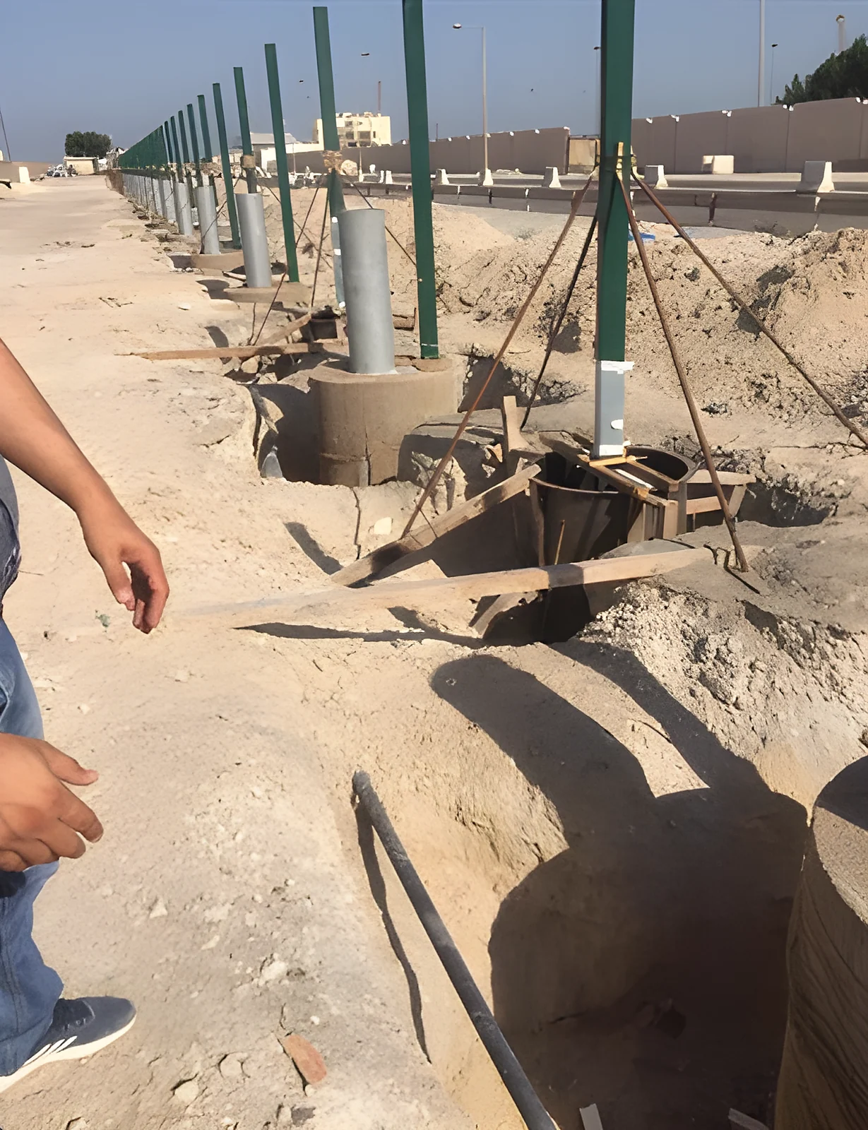 A line of fence posts being set across the site